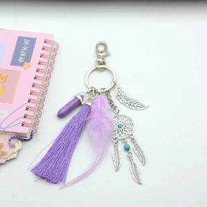 Bohemian dreamcatcher keychain with purple feathers and tassels on white background