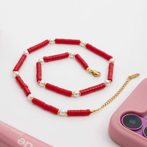 Detailed macro view of a red bead and pearl necklace with golden lobster clasp closure