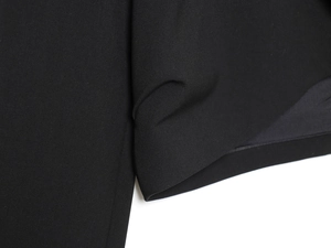 Close-up of black shoulder-padded blazer showing fine stitching and fabric texture
