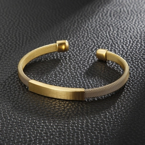 Macro detail of golden mesh bracelet featuring a brushed metal identification plate