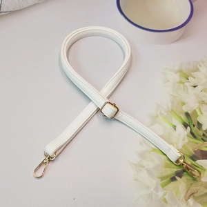 Bandoulière réglable blanche motif litchi avec boucles en métal doré sur table