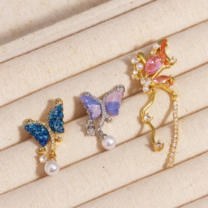 Detailed macro of asymmetric butterfly pendants with micro-pave zircons and enamel inlay