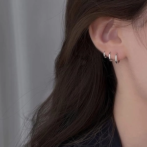 Three-piece set of polished silver stainless steel hoop earrings worn on female ear