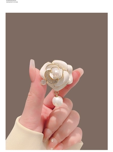 Détails de la broche camélia avec pétales blancs et un élégant pendentif en perle