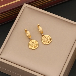 Detailed shot of golden rose embossed earrings on a beige velvet jewelry box lining