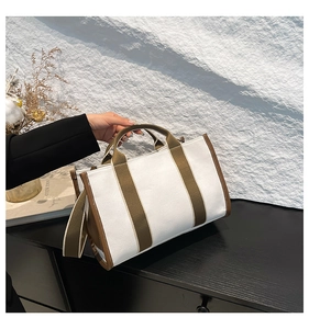 Detail of canvas tote bag with olive green straps and leather trim in interior setting