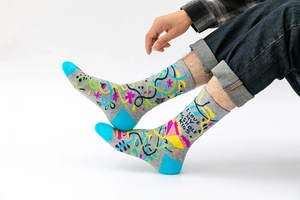 Detail of grey crew socks featuring colorful abstract patterns and funny slogan text