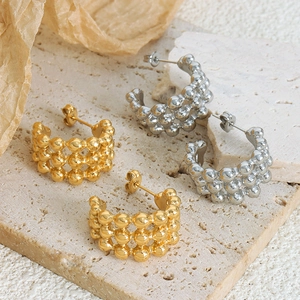Modern C-shaped beaded gold and silver earrings on elegant stone and textured paper