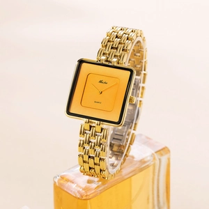 Elegant gold square quartz watch for women with metal chain strap on display stand