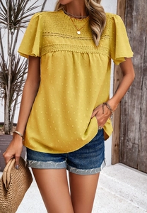 Detailed close-up of yellow short-sleeve top featuring intricate lace stitching and textured fabric