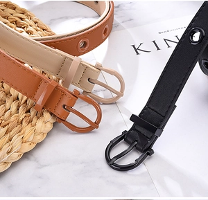 Three colors of faux leather belts with resin buckles and eyelets on a styled background