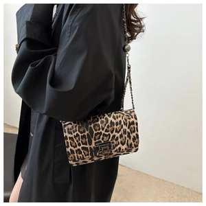 Detail of leopard print crossbody bag featuring a metal lock and dark chain strap