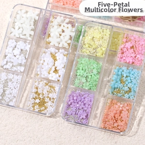 Macro detail of colorful resin five-petal flowers and metallic micro beads for nail art