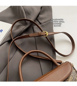 Detail of adjustable shoulder strap and golden metal buckle on brown crocodile bag