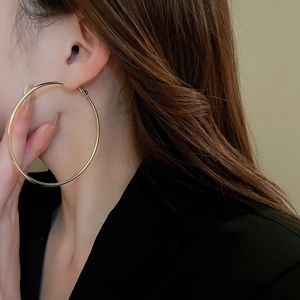 Close-up of oversized gold-finish minimalist hoop earrings worn with sleek styling
