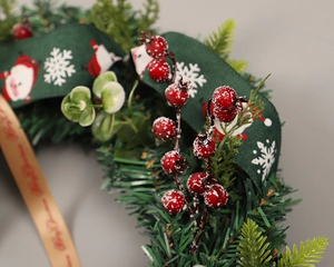 Detailed close-up of Christmas wreath with snowy red berries and festive ribbons