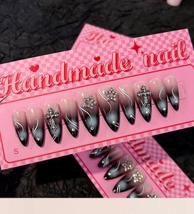Détail de faux ongles faits main dégradé noir avec croix argentées et breloques étoiles