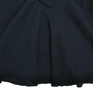 Gros plan sur le tissu texturé sombre montrant les plis détaillés et l'ourlet de la robe