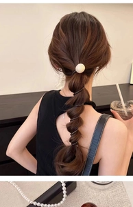 Detail showing white pearl hair clip and black spiral hair tie on a ponytail