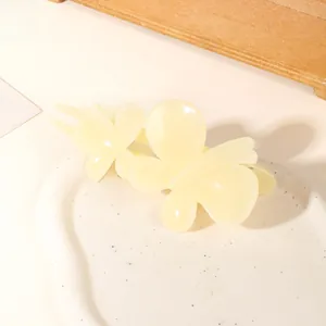 Detail of a creamy yellow butterfly hair clip on a minimalist stone display tray