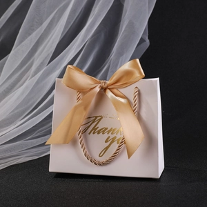 Elegant white wedding favor bag with golden Thank You text and a satin silk bow