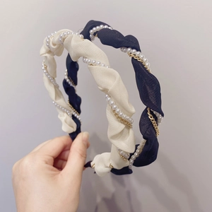 Detailed close-up of pleated fabric headband with artificial pearls and golden chain links