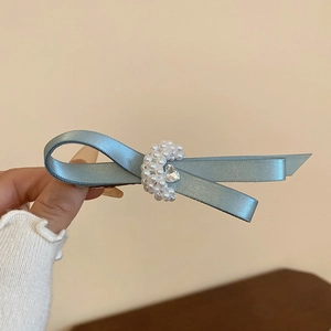 Close-up of elegant mesh bow hair clip with pearls and heart crystal in dusty blue