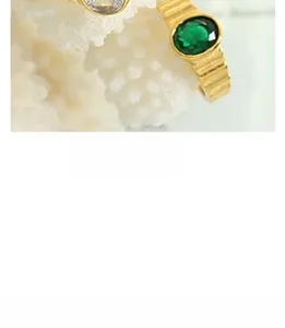 Macro shot of vintage gold rings with green emerald stone and detailed relief engravings