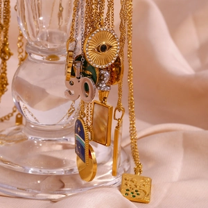 Detail of layered gold and silver necklaces with evil eye and number pendants on silk