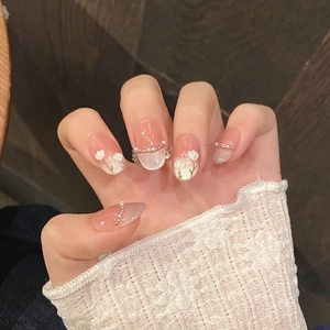 Detail of pink gradient almond nails with 3D white flowers and tiny pearl accents
