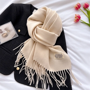 Detail of soft beige faux cashmere scarf showing fringe texture and woven label