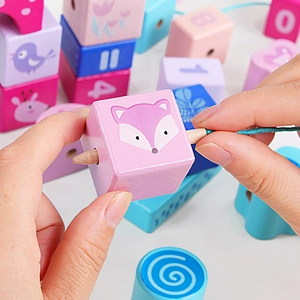 Close-up of child threading a wooden needle through colorful animal and number blocks