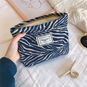 Detail of blue zebra pattern chenille makeup bag with 'TIME TO PARTY' woven label