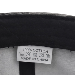 Detailed macro view of the 100% cotton material care label inside the camo baseball cap