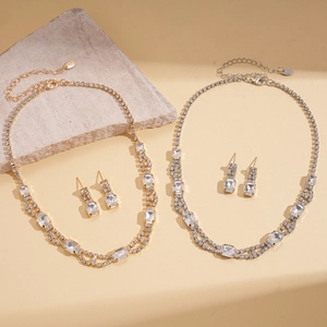 Macro shot of gold and silver square rhinestone necklace and earring jewelry sets on stone