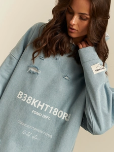 Oversized light blue distressed hoodie with white print text and ripped design details