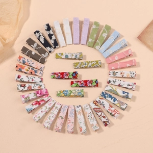 Flat lay of colorful floral fabric wrapped BB hair clips and duckbill clips in diverse patterns