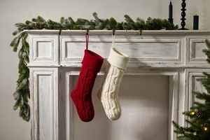Detail of knitted Christmas stockings hanging on a vintage fireplace with pine decoration