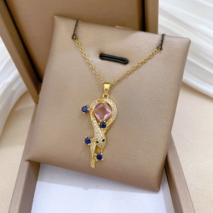 Macro detail of gold snake necklace with pink square gemstone and blue crystal halo