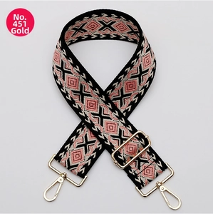 Close-up of geometric pink and black woven adjustable bag strap with gold metal hooks