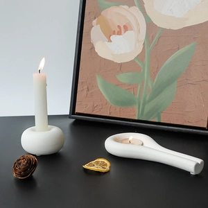 Modern white ceramic candle holders in donut and spoon shapes on a black table