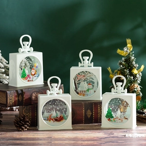 Close-up of portable Christmas lantern set with festive miniature scenes and warm light