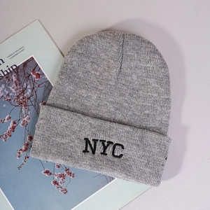 Detailed close-up of grey knitted beanie featuring black NYC embroidery and thick texture