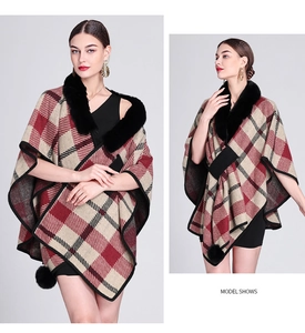 Detail of red and beige knit poncho with faux fur collar and black pom-pom trim on model