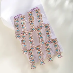 Detail of luxury long tassel earrings with pink and blue gemstones on display card