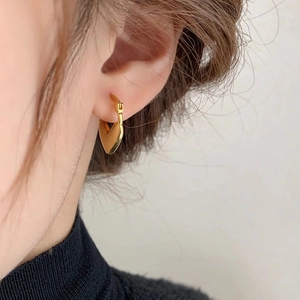 Detail of a minimalist gold heart earring with pavé zircon on a model wearing black