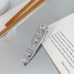 Close-up of silver hair clip with zircon inlay on a reflective mirror surface
