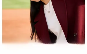 Silver heart pendant necklace on a model with a dark red coat and orange background