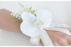 Detailed view of white orchid wrist corsage with silk ribbons for wedding bridesmaids