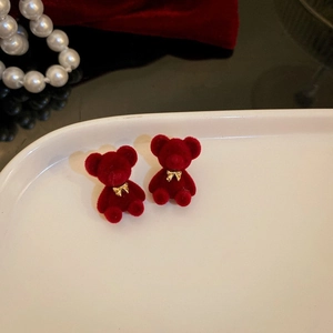 Dettaglio di orecchini a forma di orsetto rosso floccato con fiocchi d'oro per Natale